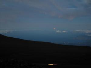 Full moon setting over the water in the West before sunrise
