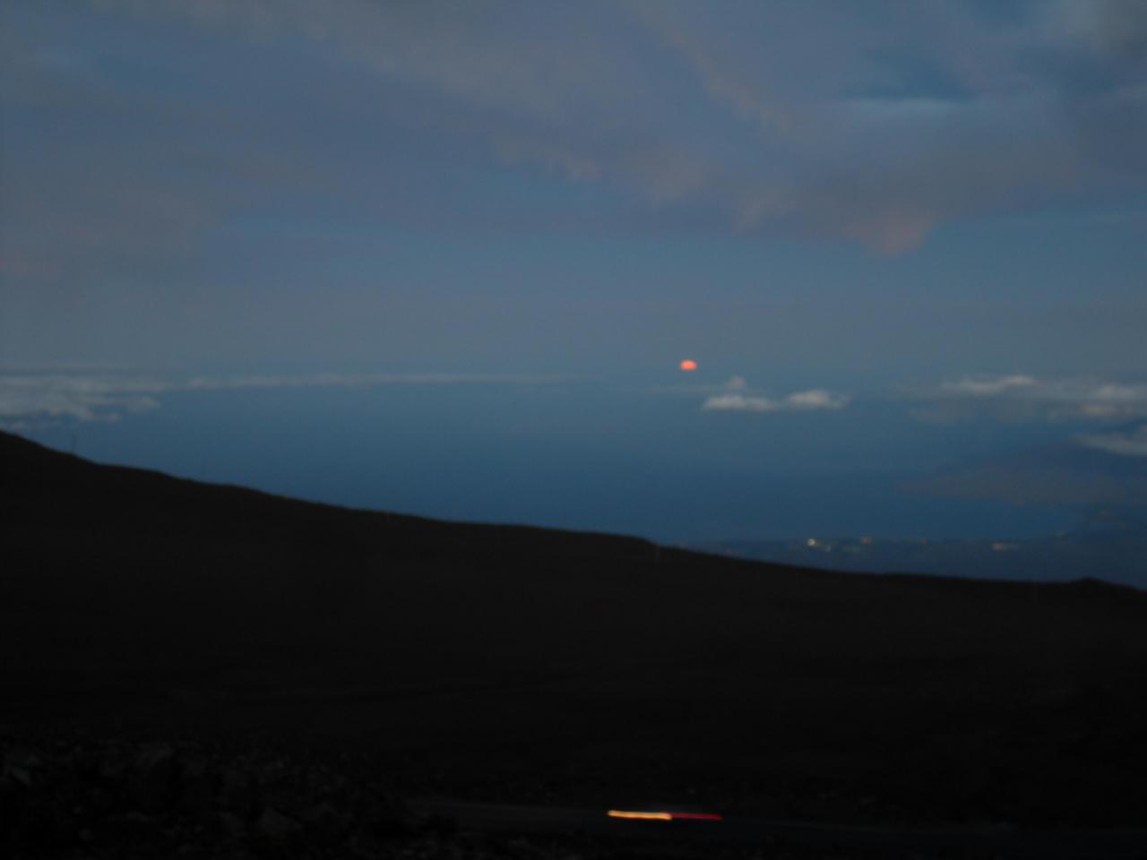Full moon setting over the water in the West before sunrise